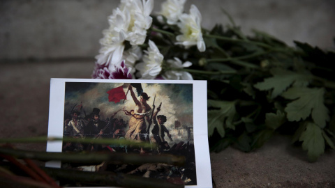 Icónica imagen de un ramo de flores junto a una fotografía del cuadro La Libertad guiando al pueblo.