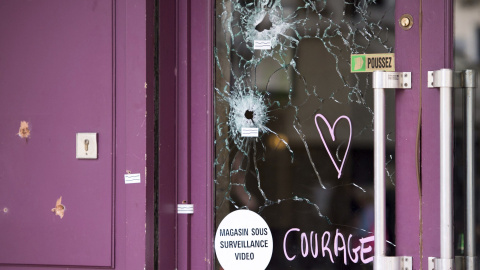 Un corazón y la palabra "coraje" junto a los impactos de bala en uno de los cristale del restaurante Casa Nostra en la Rue de la Fountaine au Roi de París.- EFE