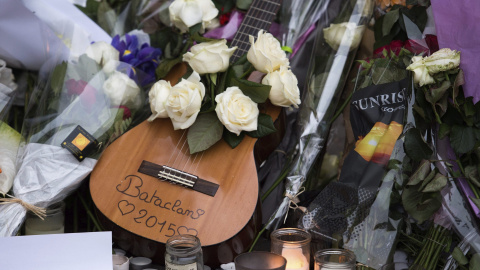 Una guitarra rodeada de flores y velas encendidas que fueron depositadas frente a la sala de fiestas Bataclan en memoria de las víctimas de los atentados del viernes en París.- EFE