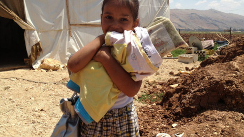 Niña siria refugiada en Líbano sostiene una 'muñeca' hecha con un trozo de madera / ACNUR