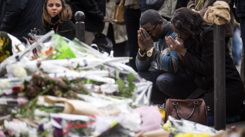 Numerosas personas guardan un minuto de silencio como homenaje a las víctimas de los atentados del viernes en la capital francesa ante el bar le Carillon de París. EFE