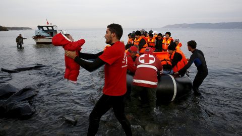 Un voluntario coge a un bebé refugiado en la playa de la isla griega de Lesbos. REUTERS/Yannis Behrakis