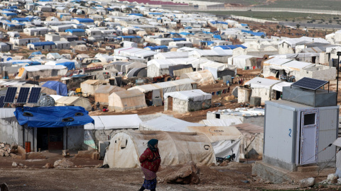 Una mujer siria desplazada camina por el campamento Atmah IDP, ubicado cerca de la frontera con Turquía, Siria. -Reuters