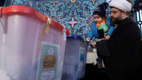 Un hombre y un niño junto a las urnas electorales durante las elecciones en Irán.- REUTERS