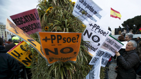 Una mujer coloca unas pancartas en un arbusto durante las Marchas de la Dignidad. REUTERS / Sergio Pérez