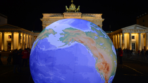 Un globo terráqueo iluminado junto a la Puerta de Brandeburgo. - AFP