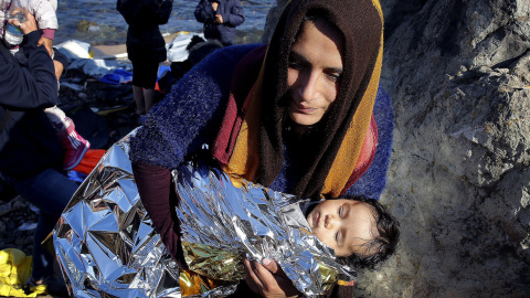 Una inmigrante afgana lleva a su bebé tras llegar en una patera a la isla griega de Lesbos. REUTERS / Yannis Behrakis