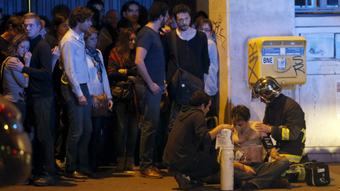 Un joven es atendido por dos bomberos cerca de la sala Bataclan en la noche del 13-N. /REUTERS