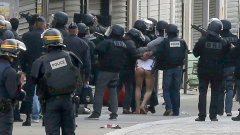 Un hombre sin pantalones es arrestado por las fuerzas espaciales de la Policía francesa durante la operación de búsqueda del terrorista fugado de los atentados de París, en Saint-Denise, Francia.- REUTERS / Jacky Naegelen