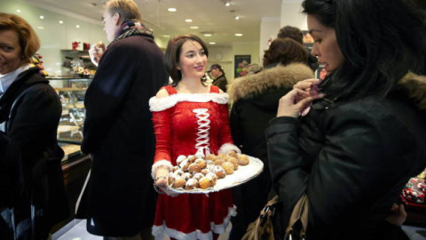 Una joven sirve postres navideños en una pastelería.- EFE