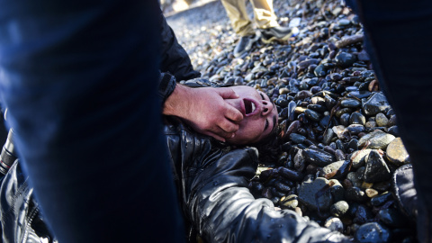 Una mujer herida se encuentra en la orilla después de llegar con otros inmigrantes y refugiados a la isla griega de Lesbos después de haber cruzado el Mar Egeo de Turquía el 26 de noviembre de 2015. AFP / BULENT KILIC