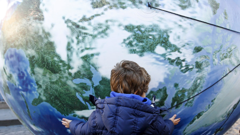 Un niño abraza un globo enorme con forma de mundo en la marcha por el clima en Roma, Italia./ REUTERS/Alessandro Bianchi