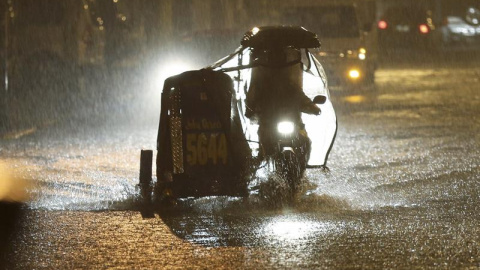 Un vehículo circula bajo una intensa lluvia por una calle inundada en Manila (Filipinas). Al menos una persona ha muerto y 733.000 más tuvieron que ser evacuadas en Filipinas debido al tifón Melor, que desde ayer azota la región central del