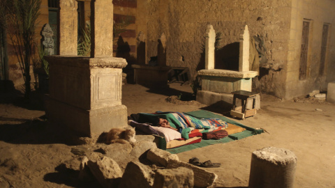 Un hombre duerme entre varias tumbas frente a su vivienda de una sola habitación en la Ciudad de los Muertos, la necrópolis de El Cairo donde habitan desce hace cientos de años docenas de miles de personas. REUTERS/Asmaa Waguih