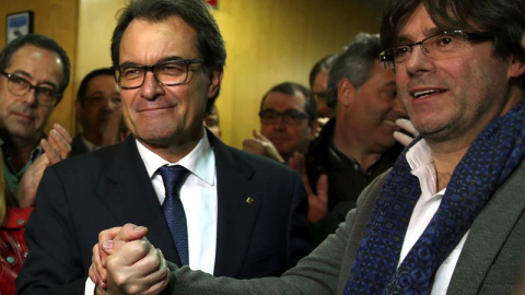 El presidente catalán en funciones, Artur Mas (i), estrecha la mano del alcalde de Girona, Carles Puigdemont (d), a su llegada a la sede de CDC tras la rueda de prensa que ha ofrecido hoy en el Palau de la Generalitat en la que ha anunciado