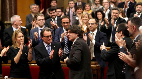 El nuevo presidente de la Generalitat, Carles Puigdemont (c), tras ser elegido durante el pleno de investidura celebrado esta tarde en el Parlament de cataluña. EFE/Alberto Estévez