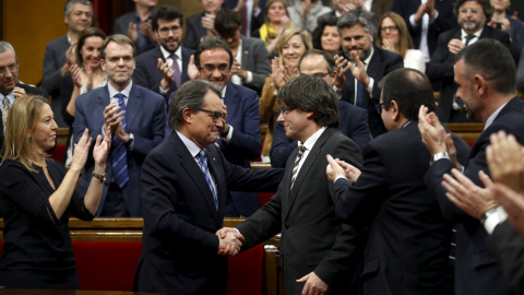 Artur Mas saluda al nuevo president de le Generalitat, Carles Puigdemont al término del pleno de investidura en el Parlament. - REUTERS