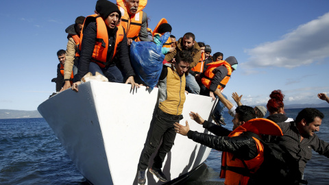 Refugiados y emigrantes saltan de un barco al llegar a la isla griega de Lesbos, en una foto de archivo./REUTERS