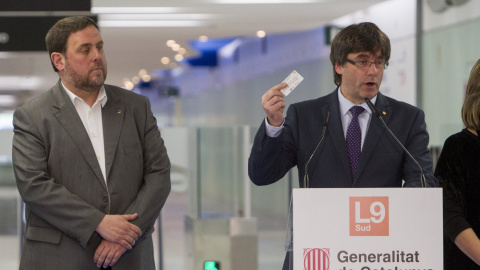 El president de la Generalitat, Carles Puigdemont, acompañado del vicepresidente del Gobierno catalán, Oriol Junqueras, muestra un billete de transporte público, durante el acto de inauguración del nuevo tramo de la Linea 9 (L9) del metro, 