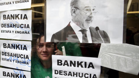 Una activista mira a través de una ventana desde el interior de la sucursal de Bankia en Madrid donde se ha llevado a cabo una protesta contra los desahucios. REUTERS/Andrea Comas