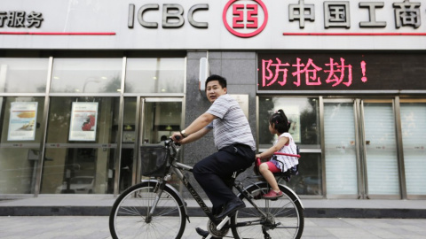 Un hombre pasa con su bicicleta por delante de una oficina del banco ICBC en Pekin. REUTERS