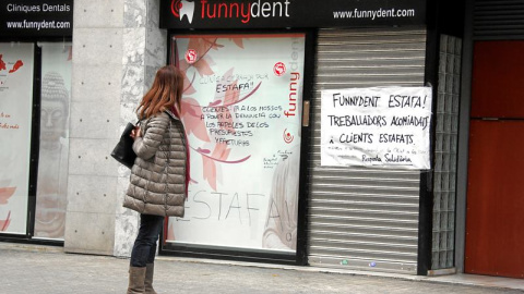 Una mujer lee la pancarta colocada en la puerta de la clínica Funnydent, en Mataró.- EFE