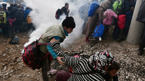 Una mujer trata de sacar a sus hijos de la zona donde la Policía macedonia ha dispersado los gases lacrimógenos. - AFP