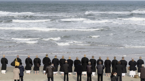 Monjes budistas y familiares de las víctimas, frente al mar, rezan en recuerdo de los fallecidos por e tsunami de marzo de 2011. REUTERS/Kyodo