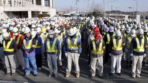 Trabajadores de la descontaminacion de la zona de  Fukushima guardan un minuto de silencio en la ceremonia en recuerdo de las víctmas del tsunami de marzo de 2011. REUTERS/Kyodo