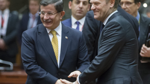 El primer ministro turco Ahmet Davutoglu (izda) se estrecha la mano con el presidente del Consejo Europeo Donald Tusk, durante la cumbre de los jefes de Estado. EFE/Olivier Hoslet