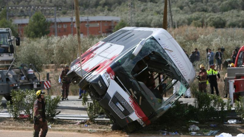 Efectivos del cuerpo de bomberos en el momento de levantar el autocar perteneciente a la empresa de Mollet del Vallès (Barcelona), que esta mañana ha chocado contra un vehículo en la autopista AP-7, a la altura de Freginals (Tarragona). Tre