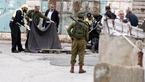 Soldados israelíes cubren el cuerpo sin vida de un palestino en Hebrón (Palestina) hoy, 24 de marzo de 2016.- EFE/Abed Al Hashlamoun