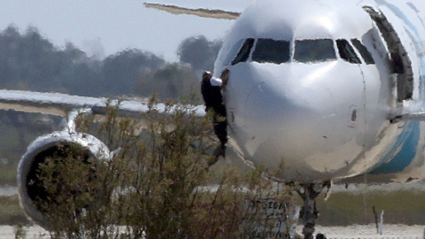 Dos hombres de los cuerpos de seguridad escalan por el avión egipcio secuestrado por un hombre en el aeropuerto de Chipre. REUTERS