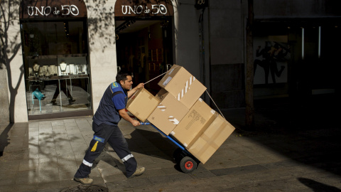 Un trabajador transporta en una carretillas varios paquetes por el centro de Madrid. REUTERS