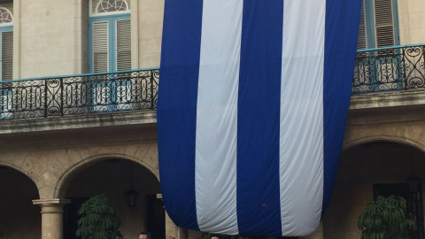 Ciudadanos cubanos llevan el nombre del comandante en sus camisetas y posan junto a la bandera cubana. Lucía Martínez Quiroga