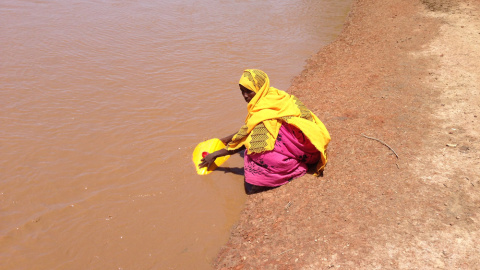 Mujer recogiendo agua en un río en Burkina Faso. / AUARA