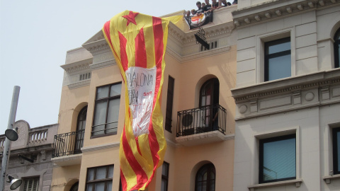 Varias personas despliegan una estelada en un edificio en Badalona,