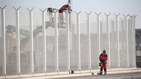 Operarios franceses colocan alambres de púas en una valla del puerto de Calais. /  REUTERS