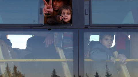 Varias personas saludan desde el autobús con el que van a ser evacuados de Alepo. - AFP