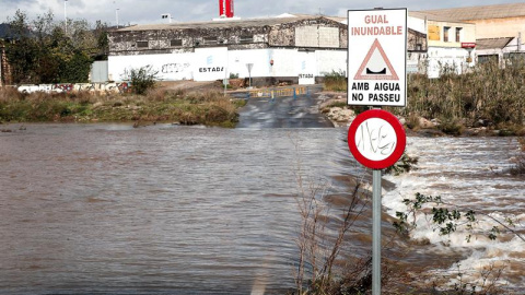 La Policía local de Sagunto ha cortado esta carretera que cruza el cauce habitualmente seco del barranco del río Palancia en Sagunto tras su crecida por las lluvias. La Agencia Estatal de Meteorología (Aemet) mantiene para hoy la alerta nar