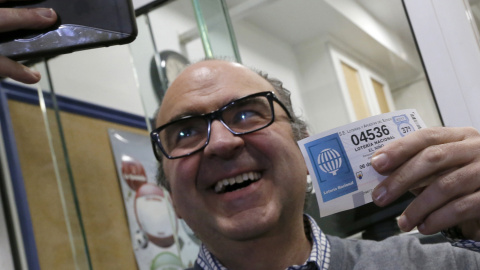 El administrador de lotería Óscar de Toro, se hace un selfie con el número agraciado con el segundo premio de la Lotería de Navidad, 4.536, vendido en su administración situada en un bar, esta mañana en Santiago de Compostela. EFE/lavandeir