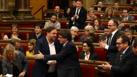 El presidente de la Generalitat, Carles Puigdemont, felicita al vicepresidente y conseller de Economía, Oriol Junqueras, al finalizar la votación en la que el Govern ha conseguido la admisión a trámite de la Ley de Presupuestos con el apoyo