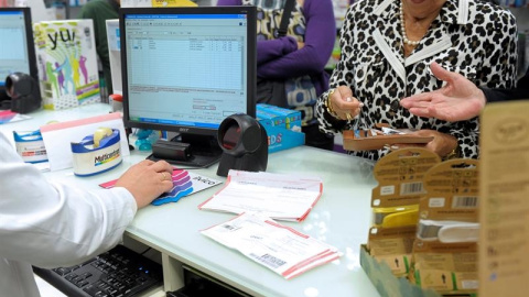 Unos pensionistas retiran sus medicamentos y pagan su aportación corespondiente al sistema de copago. EFE/Villar López