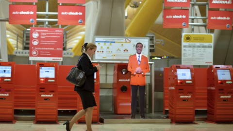 Una mujer pasa junto a los terminales de facturación de Iberia en la Terminal T4 del aeropuerto de Barajas. AFP/Pedro Armestre