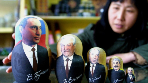 Una tendera china enseña una colección de muñecas matrioskas con las caras de Putin, Yeltsin, Gorbachov, Stalin y Lenin.- AFP