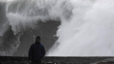 Un hombre camina cerca de las olas esta tarde en la costa de Muxía (A Coruña). | LAVANDEIRA JR. (EFE)