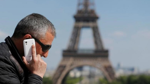 Un hombre habla por su móvil en la plaza parisina de Trocadero, con la Torre Eiffel al fondeo. REUTERS/Christian Hartmann