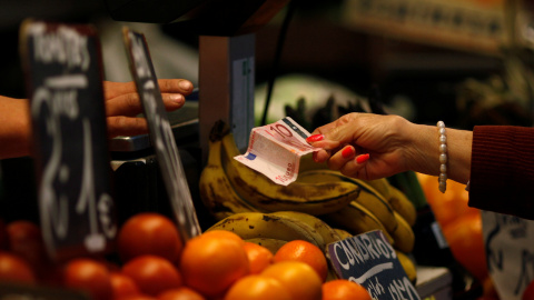 Una mujer paga después de hacer la compra en un puesto de frutas y verduras en un mercado en Málaga. REUTERS/Jon Nazca