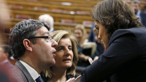 La vicepresidenta del Gobierno, Soraya Sáenz de Santamaría, conversa con los ministros, de Energía, Álvaro Nadalm y de Empleo, Fátima Báñez, durante el pleno en el Congreso de los Diputados. EFE/Fernando Alvarado