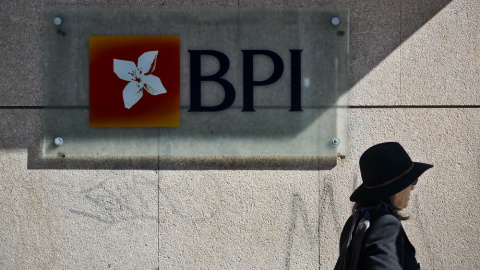 Una mujer pasa junto a una oficina del banco BPI en Lisboa.  AFP / Patricia de Melo Moreira